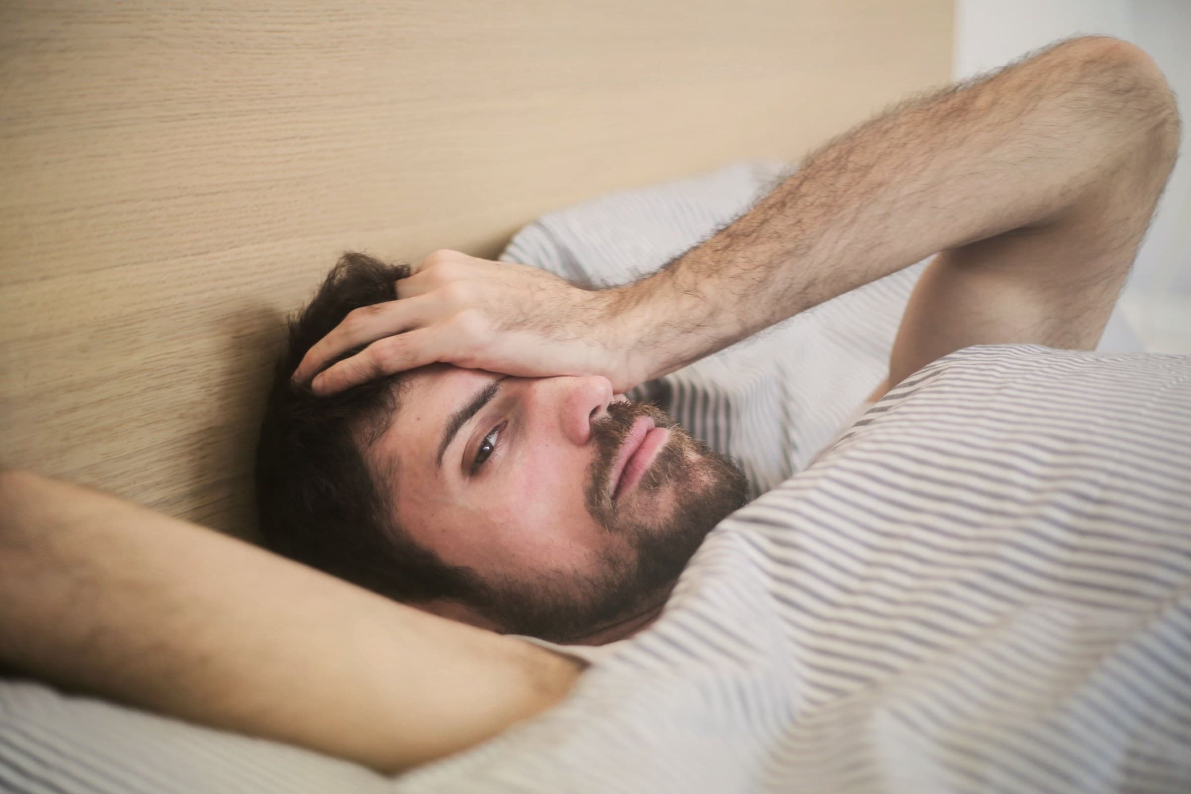 Man lying in bed looking worried