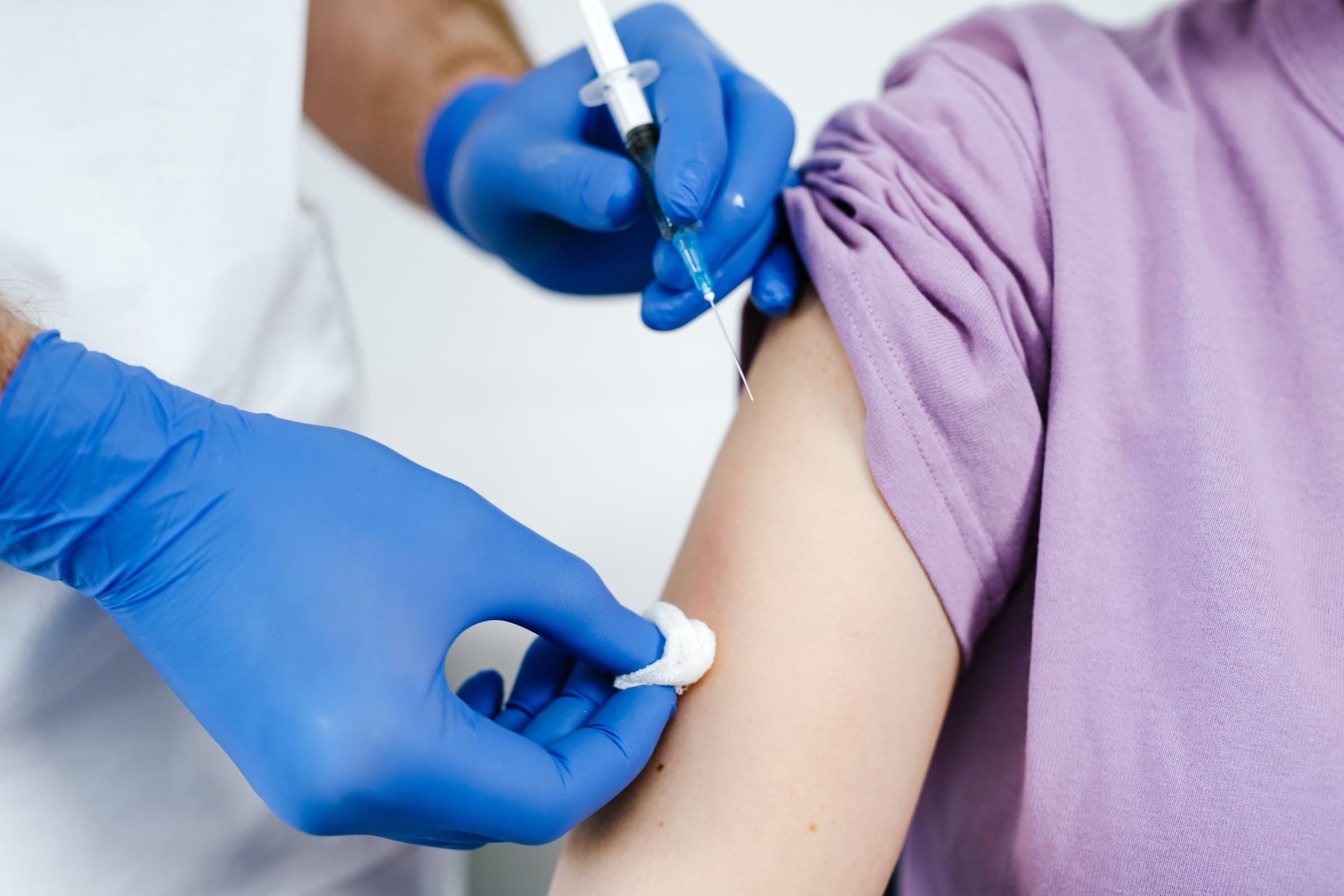 Gloved healthcare professional giving an injection in a patient's arm