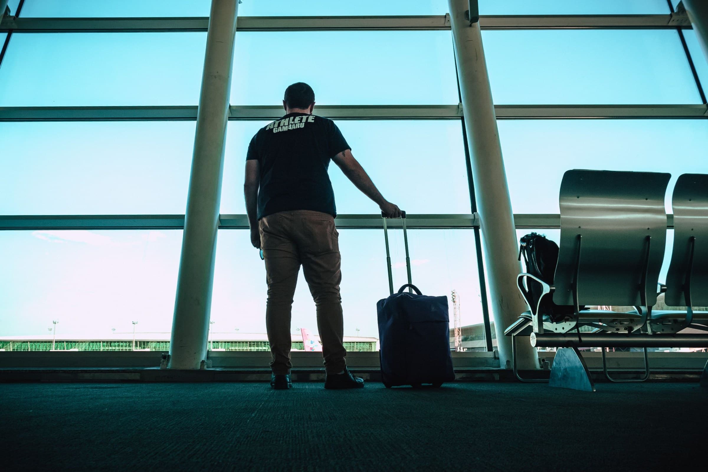 Traveller with a suitcase looking out an airport window